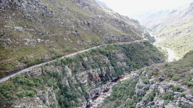  Tarmac road snaking through mountains camera rising up to reveal Bainskloof pass aerial view of the road into the distance