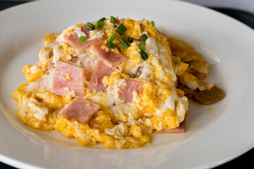 Scrambled egg and ham with rice on white dish.
