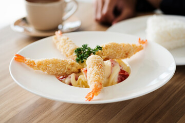 Fried shrimp with salad in white dish on a wooden table.