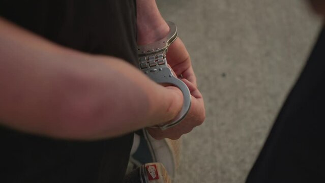 Wanted male suspect wearing handcuffs