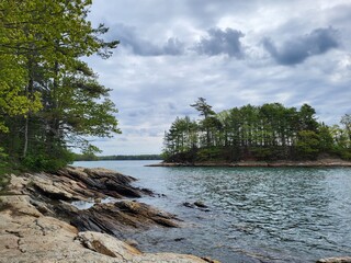 Scenic water and island with trees and clouds - obrazy, fototapety, plakaty
