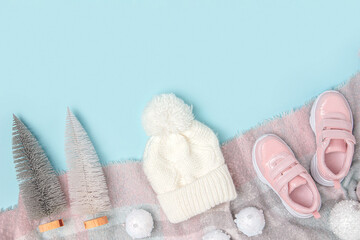 Winter background with copy space. White knitted hat, pink sneakers and scarf on blue background. Top view Flat lay