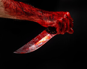 Man holding knife with bloody hand on black background.  © Михаил Решетников