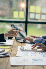 Business team meeting, teamwork concept of business merger at the office. A variety of colleagues work using graphs and computers sitting at their desks in the office. vertical picture