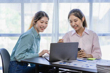 Starting a business, two young Asian women discuss working on investment projects and planning strategies. Businessman talking with laptop computer at office