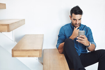 Male texting on a phone, browsing social media online while sitting on steps. Surfing the internet,...