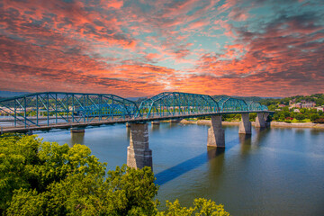 Fototapeta na wymiar a gorgeous summer landscape on the Tennessee River with the Walnut Street Bridge over the rippling blue water surrounded by lush green trees with powerful clouds at sunset in Chattanooga Tennessee USA