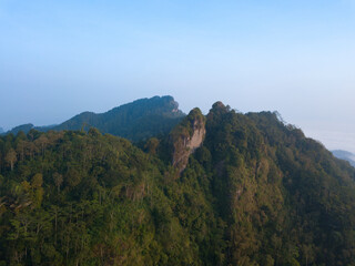 A panoramic view of the foggy Mountains with dense of forest. Blue sky with clouds over layers of green hills and mountains. Copy space.  Menoreh Hill, Central Java, Indonesia
