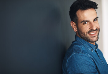 Fototapeta premium Happy, confident and smiling business man or entrepreneur in an office with copy space. Ambitious and determined male employee leaning against a wall at work. Feeling positive and working for success