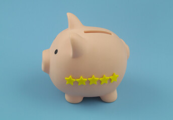 Piggy bank with 5 stars rating on blue background. Financial organization ranking concept.	