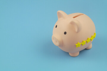Financial fund with good reputation and rating concept. Piggy bank with 5 yellow stars on blue background. Copy space for text.