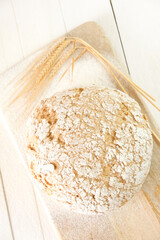 Bread and dough, ears of wheat and flour on white planks wooden table.Homebaked bread. Baking bread at home 