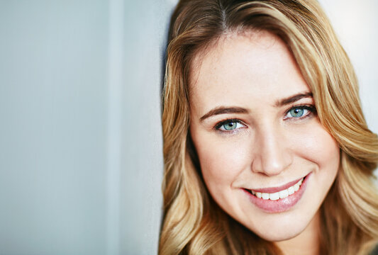 Beautiful, young and smiling female face looking happy and confident with copyspace. Closeup of a blonde natural beauty with perfect teeth and skin. Portrait of a happy, content woman alone