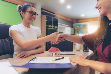 Real estate agents and customers join hands to celebrate the completion of the contract. After the approval of the home purchase and sale contract regarding home insurance and investment