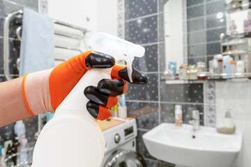 Man's hand in a protective glove with the bottle of cleaning liquid.