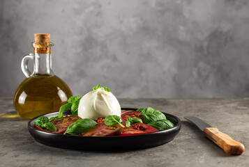 Burrata cheese served with fresh tomatoes, olive oils, and basil leaves. Delicious Italian...