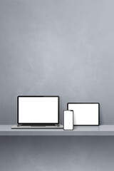 Laptop, mobile phone and digital tablet pc on grey wall shelf. Vertical background