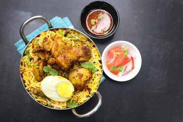 Chicken Biryani or murgh Pulao. Garnished with fried onion, mint leaves, and Boiled egg. Biryani is a Spicy nonvegetarian dish of India. Chicken cooked along with Basmati rice. Cucumber Raita.