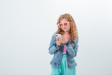 a teenage girl in sunglasses holding a phone shows surprise on a white background