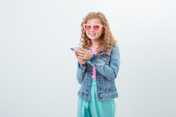 a teenage girl in sunglasses holding a phone shows surprise on a white background