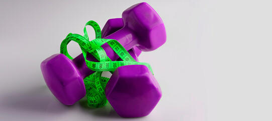 two dumbbells tied with green tape measure, fitness banner concept