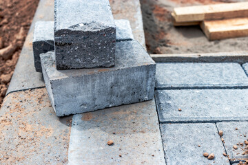 Pavement repairs and paving slabs laying on the prepared surface, with tile cubes in the background. Laying paving slabs in the pedestrian zone of the city. Paving slabs and curbs.