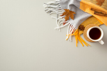 Autumn inspiration concept. Top view photo of plaid scarf cup of tea on rattan serving mat cinnamon sticks anise and yellow maple leaves on isolated grey background with empty space