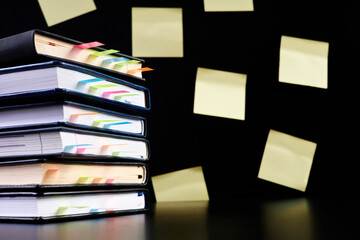 Close-up of a stack of office notepads with colorful sticky page markers sandwiched between pages...
