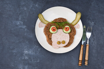 Sandwich in the form of a cheerful bull made of bread,s ausages and vegetables