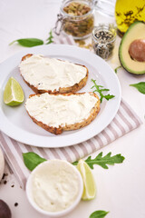 Avocado and cream cheese toasts preparation - grilled or toasted bread with cheese smeared 