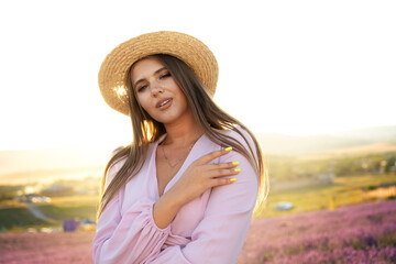 Young woman in a straw hat walking in a lavender field
