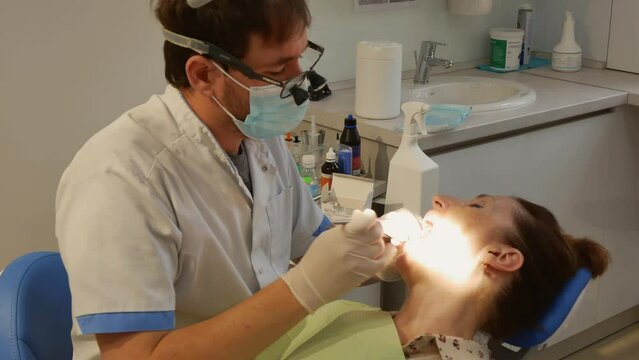 Dental clinic. The doctor prosthetics the teeth of an adult woman.