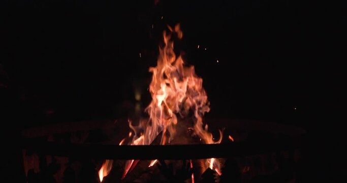 side angle of man poking fire pit with log.