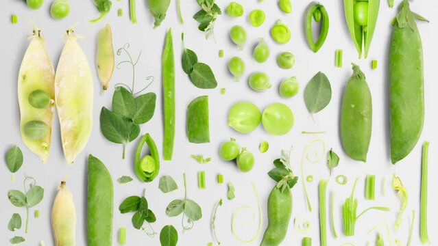 Pea vegetable pieces, slices and leaves being moved upwards isolated on white. Top view. Seamless looping. High quality 4k video.