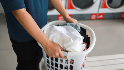 Man doing launder holding basket with dirty laundry of the washing machine in the public store....