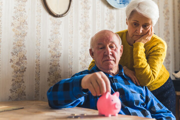 Sad, lost and worried caucasian senior couple counting coins taken out from a piggy bank while...