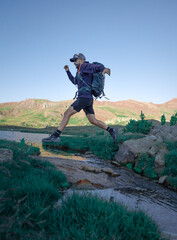 Deportista saltando río en la montaña, trail running