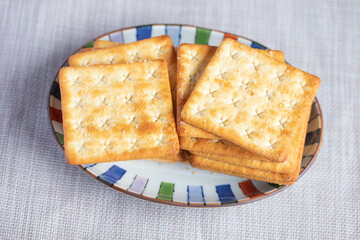 A pile of dry, thin crackers in a cup. Natural light.
