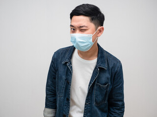 Positive man jeans shirt wear medical mask funny emotion close one eye portrait