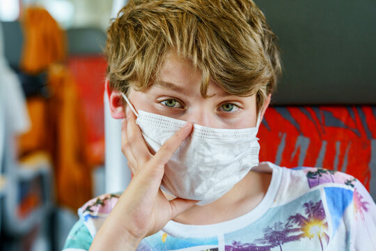 Boy wearing protective mask in bus or train. Sad school kid child.