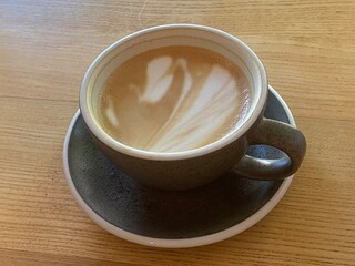 Cappuccino on table in a cafe, Close up hot cappuccino coffee cup latte art on light brown old wood table at cafe, food and drink concept.