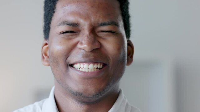Closeup of a happy business man laughing at a funny joke, being carefree and having fun at work alone. Portrait of the face of a young, smiling and positive professional being silly and goofy