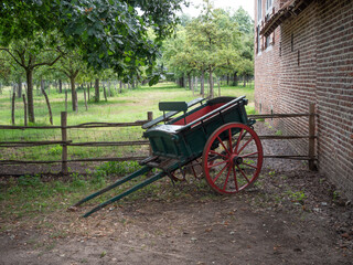 Fototapeta na wymiar Green antique handcart with red wheels from the 1880s to the 1930s