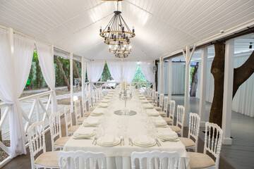 Empty banquet hall ready to receive guests on the summer terrace. white festive table
