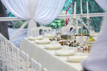 Empty banquet hall ready to receive guests on the summer terrace. white festive table