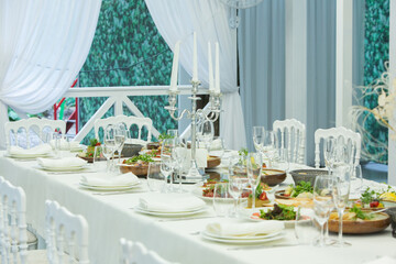 Empty banquet hall ready to receive guests on the summer terrace. white festive table