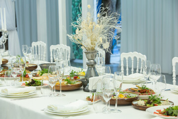 Empty banquet hall ready to receive guests on the summer terrace. white festive table