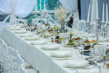 Empty banquet hall ready to receive guests on the summer terrace. white festive table