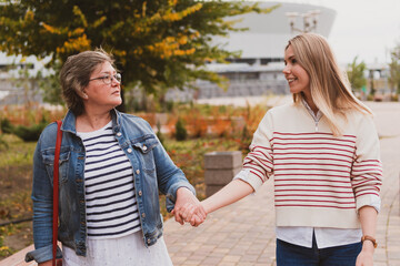 Obraz premium charming women in casual style, mom and daughter are walking in a beautiful autumn park