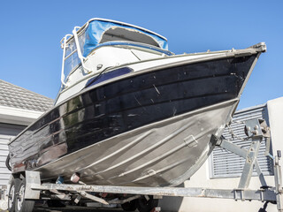 Small aluminum motorboat on trailer parked in driveway.